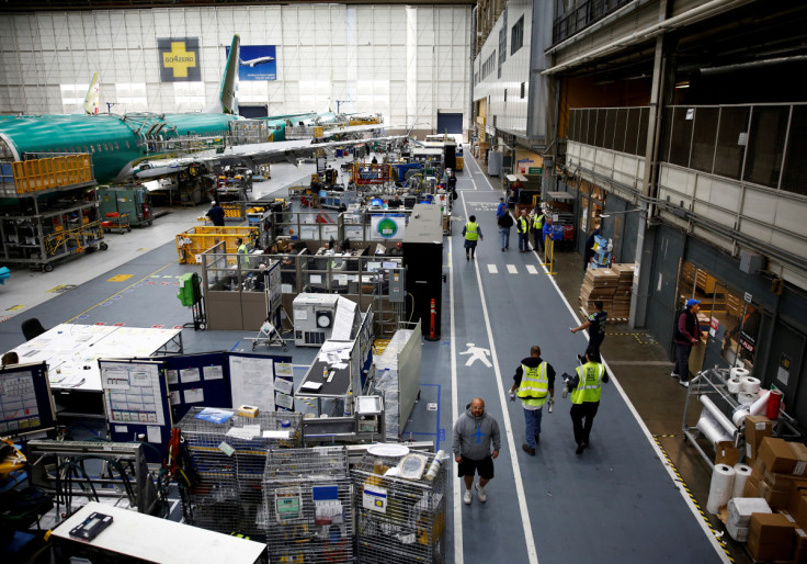 Workers walk by a 737 Max aircraft on the production line at the Boeing factory in Renton