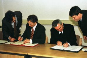 British Prime Minister Tony Blair (L) and Irish Prime Minister Bertie Ahern sign the peace agreement..