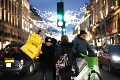 People carry shopping bags as they walk past Christmas themed shop displays on Regent Street in London