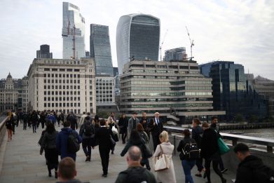 People walk over London Bridge towards the City of London financial district during rush hour in London