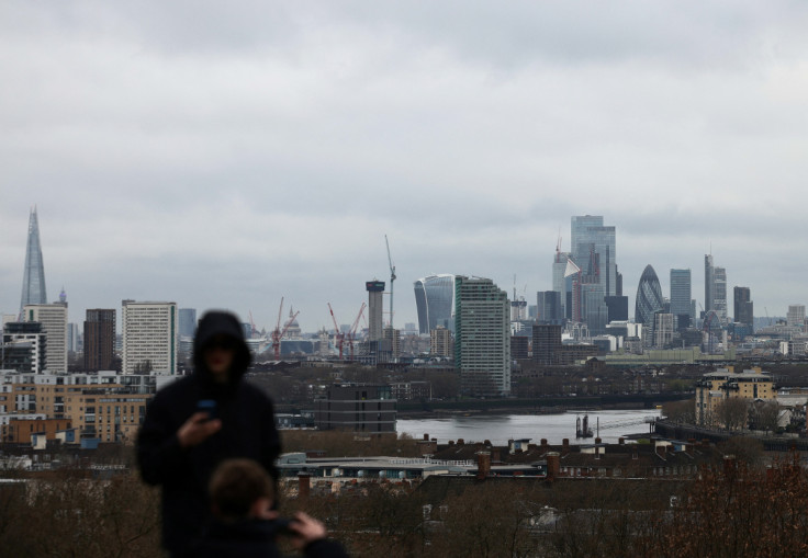 People lookout from Greenwich Park, with the City of London financial district in the distance, in London