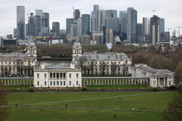 People walk through Greenwich Park, with the Canary Wharf financial district in the distance, in London,
