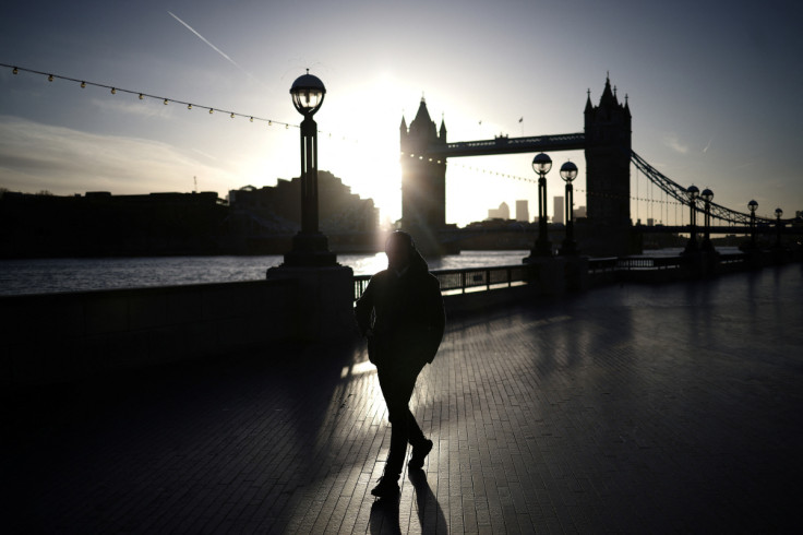 A person walks alongside the River Thames during sunrise in London