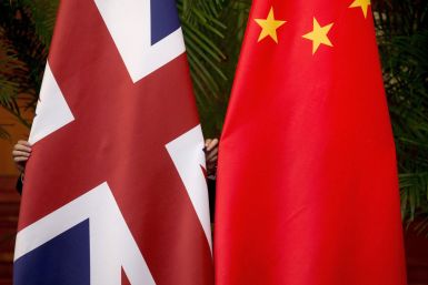 A worker adjusts British and China national flags on display for a signing ceremony at the seventh UK-China Economic and Financial Dialogue "Roundtable on Public-Private Partnerships" in Beijing