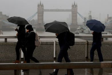 Commuters walk across London Bridge toward the financial district, in London