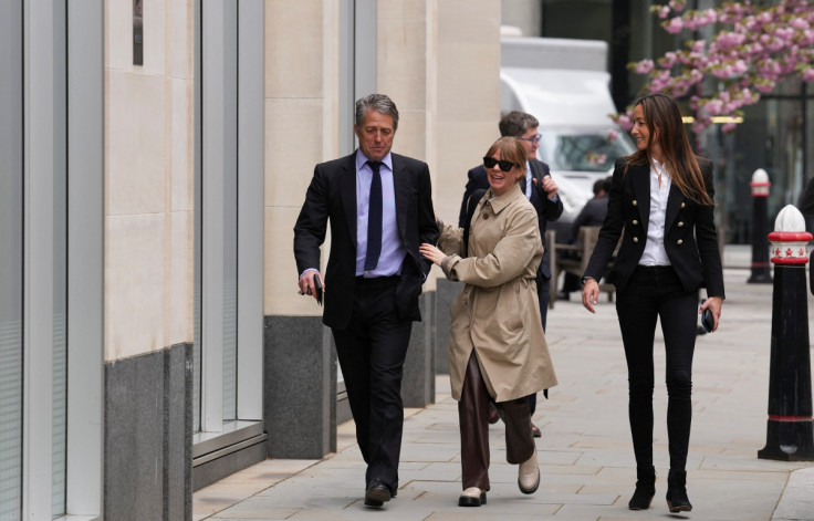 Hugh Grant and his wife Anna Eberstein walk outside the High Court, in London