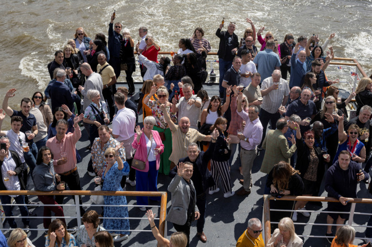 People wave from a boat, a day after Britain's King Charles and Queen Camilla's coronation ceremony, in London