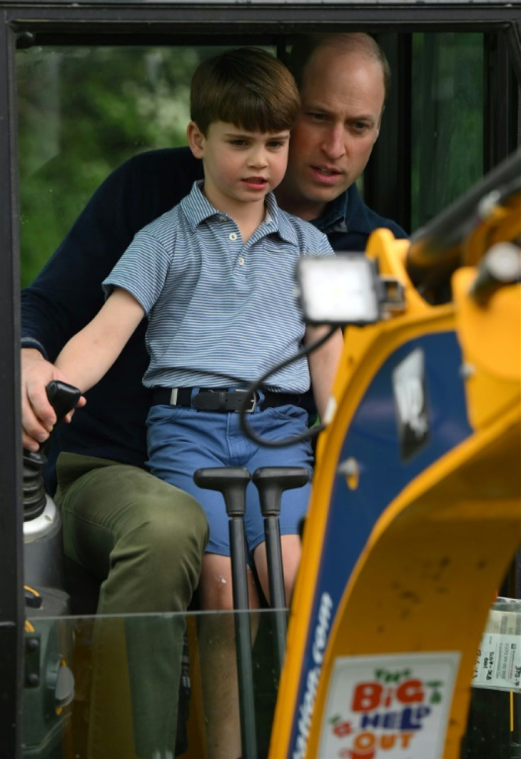 Britain's Prince Loius, with his father Prince William, the heir to the throne, aboard an excavator while taking part in the Big Help Out, during a visit to a scout hut in Slough, west of London on Monday