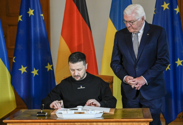 Ukraine's President Volodymyr Zelensky signs the guestbook at the Bellevue Palace before heading into talks with Germany's President Frank-Walter Steinmeier