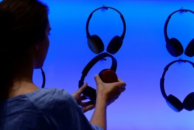 A woman poses at an installation showing headphones at the booth of JVC at the IFA (Internationale Funkausstellung) electronics trade fair in Berlin on September 1, 2016