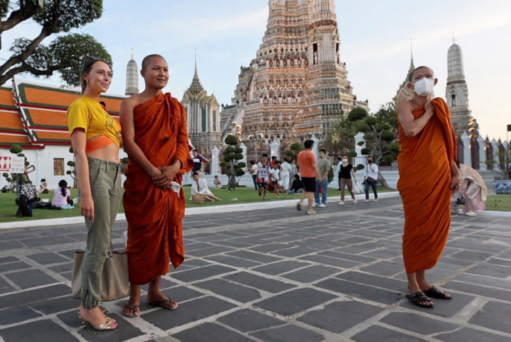 Lillian Smith, 30, from Mississippi, poses for a picture with monks in Bangkok