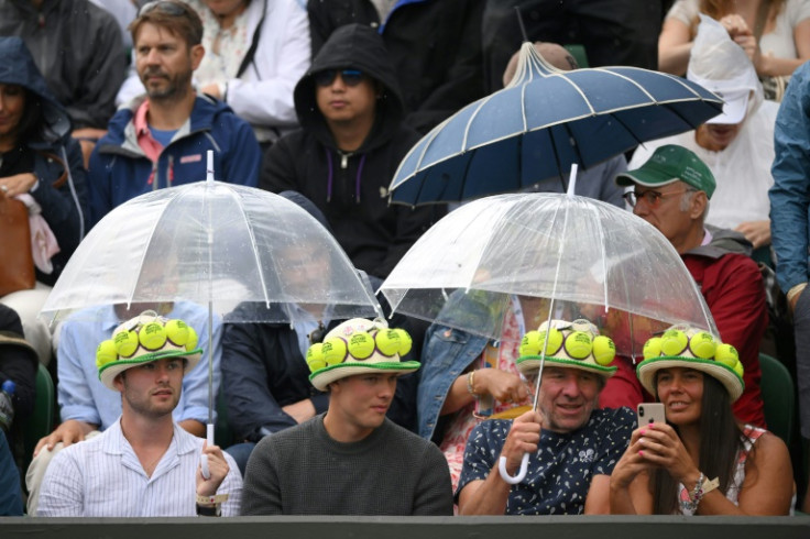 Rain pain: Fans take shelter under their umbrellas