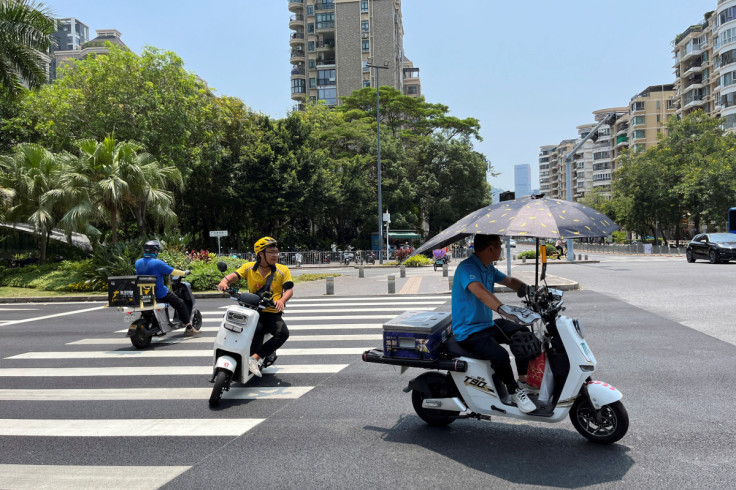 Delivery workers ride scooters in the sun