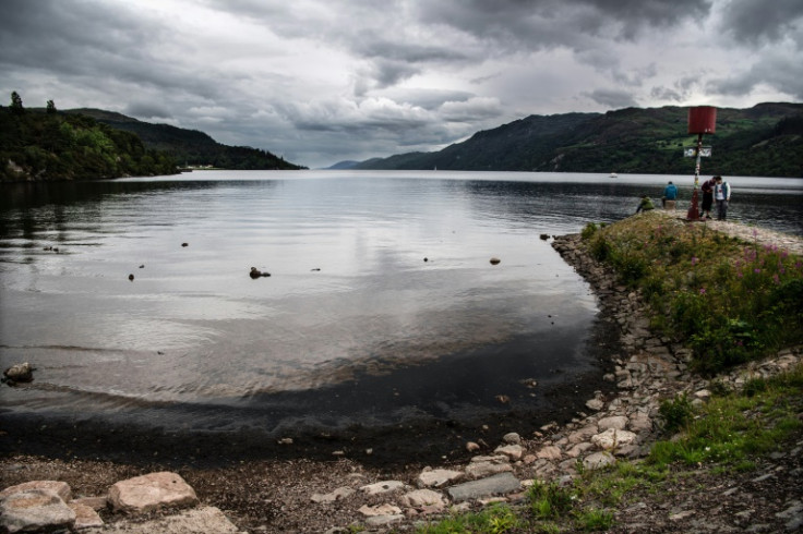 Visitors look at the water of Loch Ness, which is experiencing lower than average water level