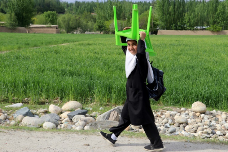 A school girl carrying a chair walks along a road on her way back home in Badakhshan Province in Afghanistan