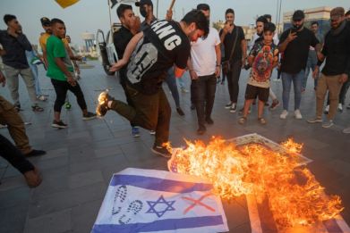Iraqis burn Israeli flags at a Baghdad rally after Hamas militants launched a deadly air, land and sea assault from the Gaza Strip