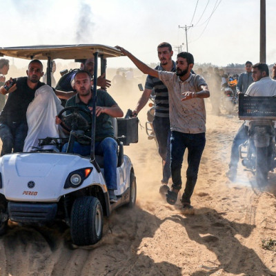 Palestinian militants ride a vehicle carrying what is reportedly an Israeli hostage under a white sheet, in Khan Yunis in the southern Gaza Strip, on October 7, 2023