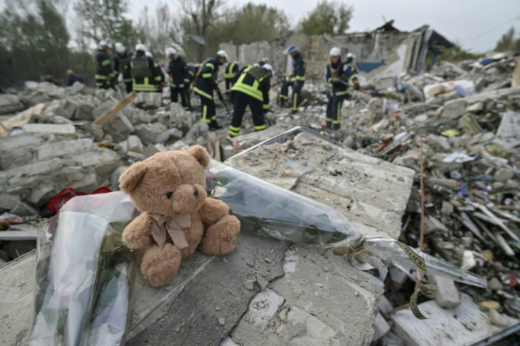 A teddy bear and flowers are displayed on the fragment of a wall in the village of Groze where over 50 people were killed by a missle strike