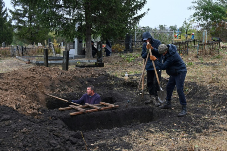 Local residents dig graves at the cemetery in the village of Hroza two days after a Russian strike killed over 50 people