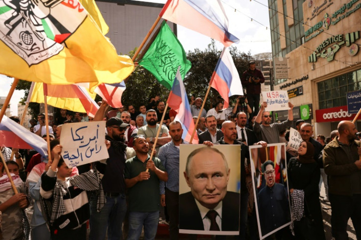 People wave Russian, Palestinian, Fatah and Hamas flags and carry portraits of Russia's President Vladimir Putin and North Koren leader Kim Jong Un on the streets of the occupied West Bank city of Hebron