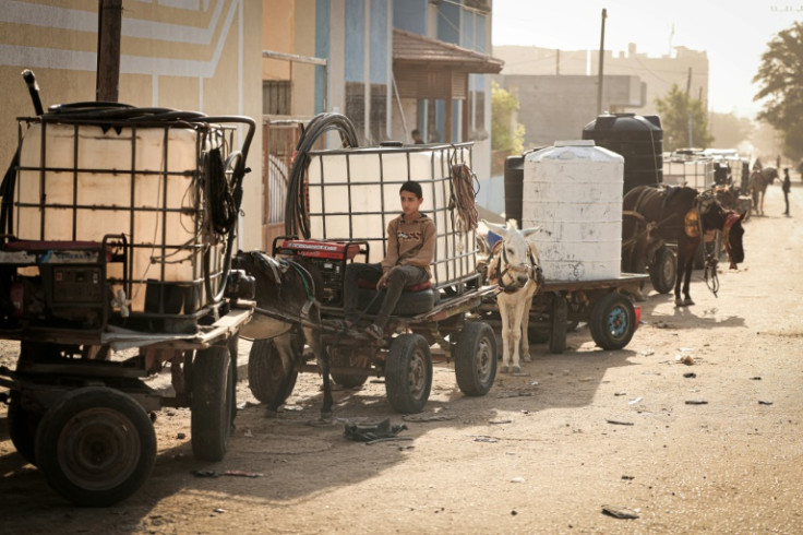 A boy sits on donkey-drawn cart loaded with a water tank in Khan Yunis in the southern Gaza Strip on October 30, 2023