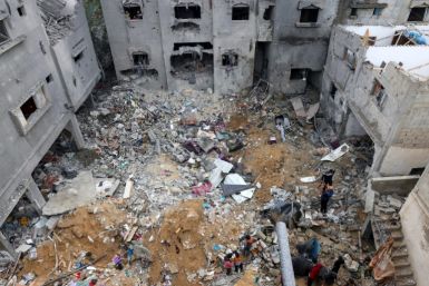 People salvage belongings in the rubble of damaged buildings following strikes in southern Gaza
