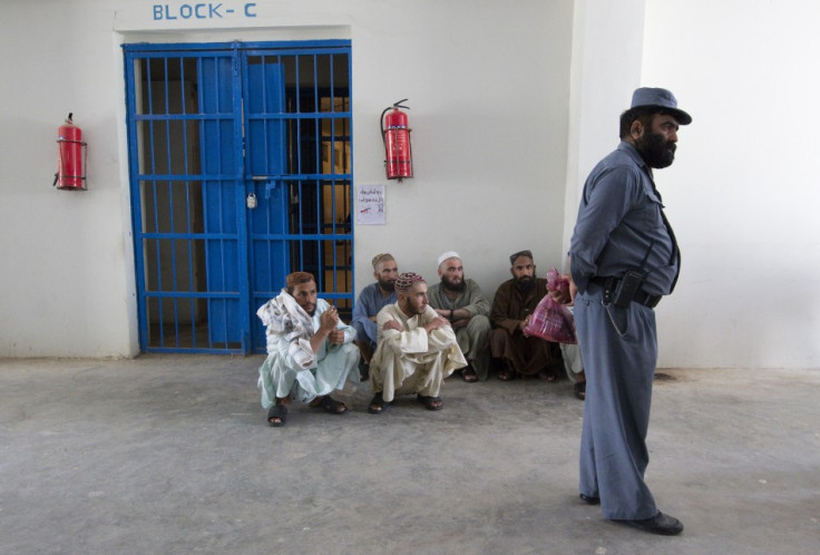 An Afghan policeman stands in front of inmates in a prison in the town of Lashkar Gah in Helmand province, southern Afghanistan
