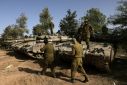 Israeli soldiers gather around tanks lined up near the border with the Gaza Strip in southern Israel on November 26, 2023