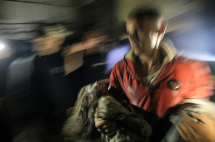 A man carries away an injured girl following an Israeli strike in Rafah in the southern Gaza Strip on December 6, 2023