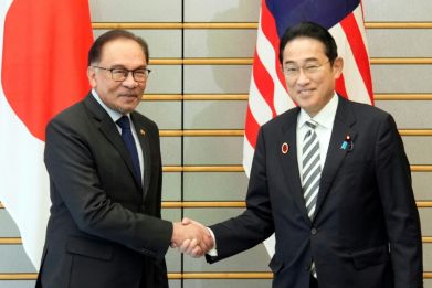 Japan's Prime Minister Fumio Kishida (R) shakes hands with Malaysia's Prime Minister Anwar Ibrahim at the start of their bilateral meeting in Tokyo