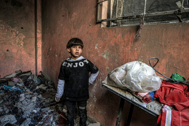 A child stands amid the rubble in a room overlooking a building destroyed by a strike in Rafah in the southern Gaza Strip on December 24, 2023