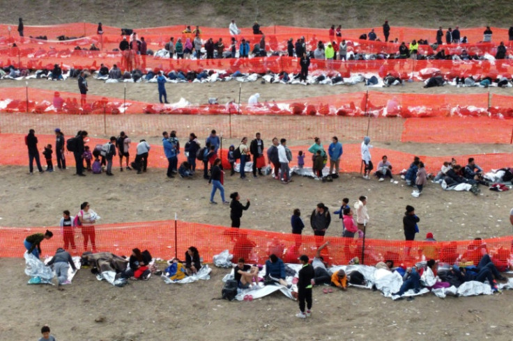 Migrants await processing by immigration authorities after crossing the US-Mexico border in Eagle Pass, Texas, December 20, 2023