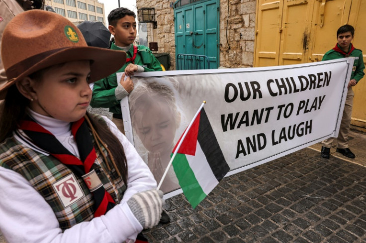 Palestinian youth members of the scouting movement hold up banners calling for an end of the conflict in the Gaza Strip