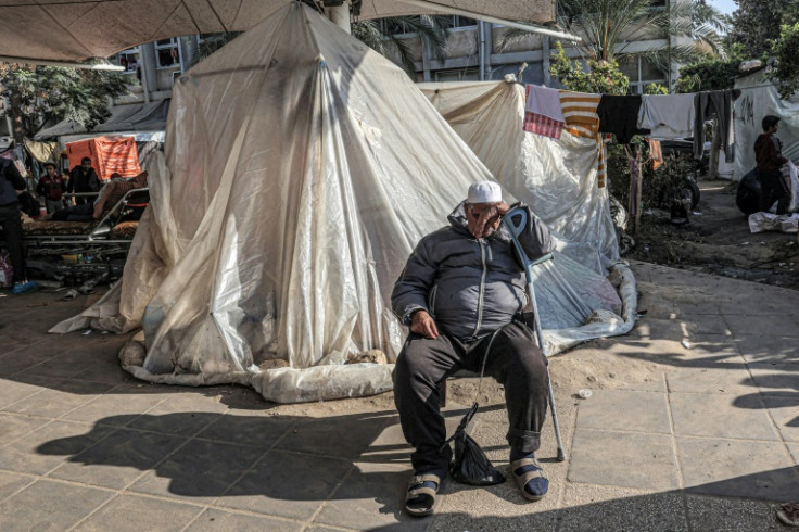 A man leans on a crutch outside a tent where displaced people are camped at the European Hospital in Khan Yunis