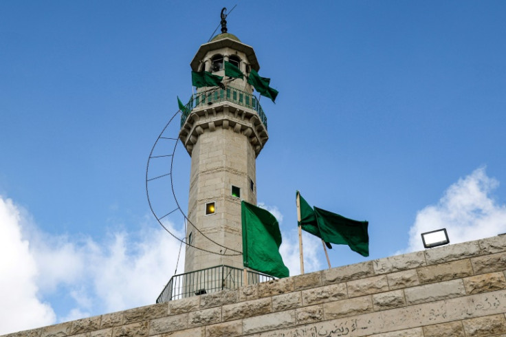 Green flags fly on the minaret of a mosque in the village of Arura, once home to slain Hamas deputy Saleh al-Aruri