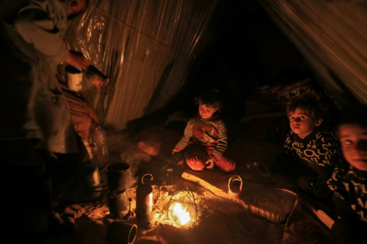 Displaced Palestinian children sit by the fire at a makeshift camp west of Rafah