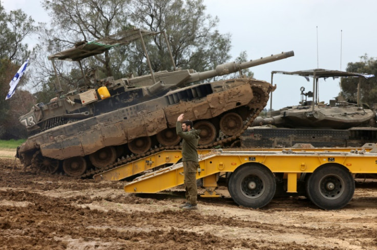 A soldier guides tanks returning to the Israeli side of the border with the Gaza Strip, after spending months in the Palestinian territory engaged in battles with Hamas militants, on January 28, 2024