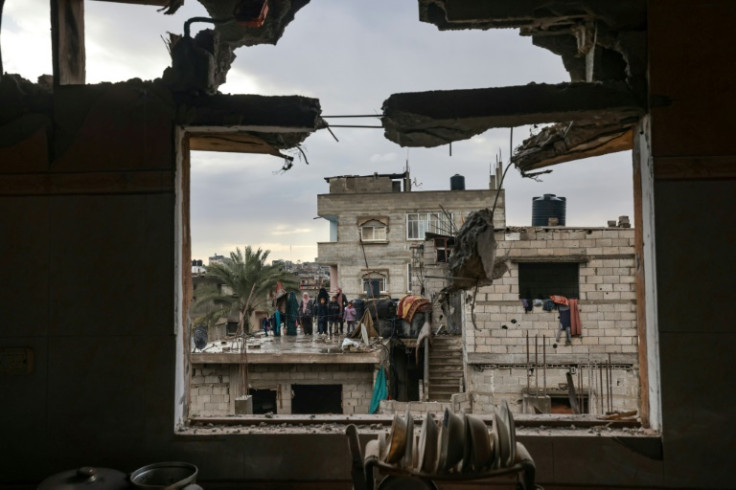 A family stands on a rooftop opposite a building damaged by Israeli bombing in Rafah in the southern Gaza Strip