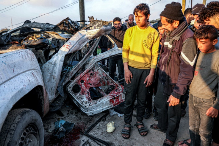 People inspect the remains of a wrecked police vehicle destroyed in an Israeli strike that killed six Palestinian policemen in Rafah