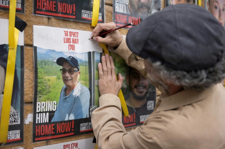 An man writes 'rescued' on a poster bearing the image of freed hostage Luis Har, in Tel Aviv