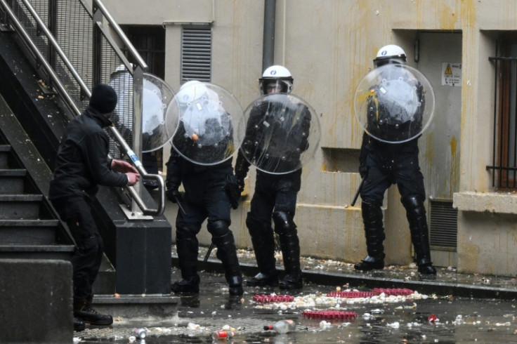 Belgian riot police shield themselves from eggs used as projectiles during a farmers' protest in Brussels, on February 26, 2024
