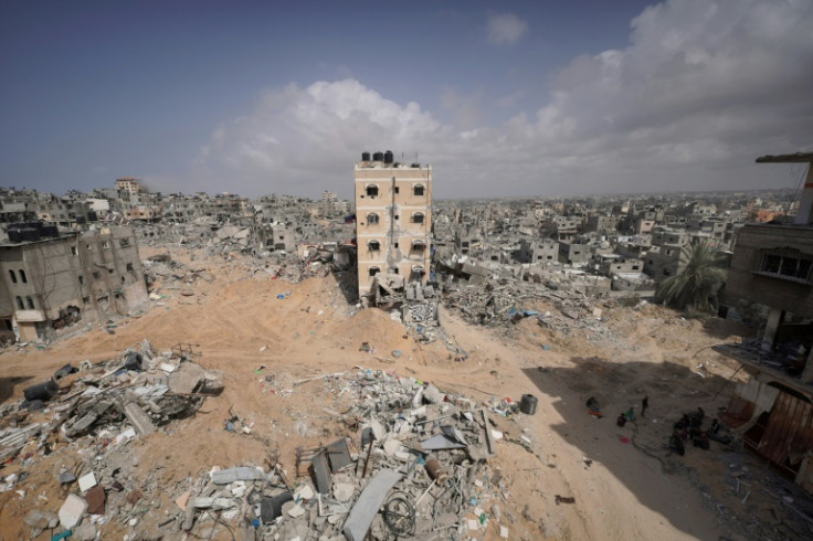 Palestinians stand amid the rubble of houses destroyed by Israeli bombardment in Khan Yunis in the southern Gaza Strip
