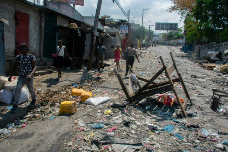 Haitians walk past a barricade March 20, 2024