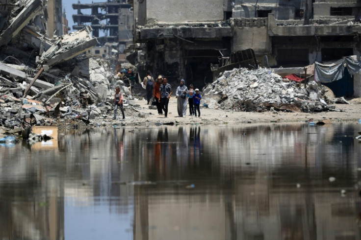 Palestinians walk near a pool of stagnant water in Khan Yunis -- the UN says Gaza's water and sanitation infrastructure has sustained 'significant damage'