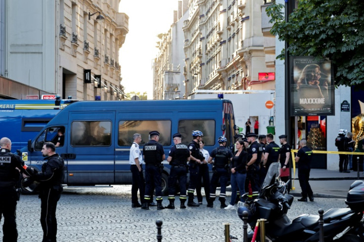 Police officers and members of a firefighting brigade secure the area in front of a Louis Vuitton store in Paris after a man attacked a police officer with a knife