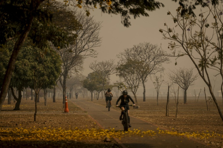 Residents of Brasilia ride bikes in the smoke-covered city