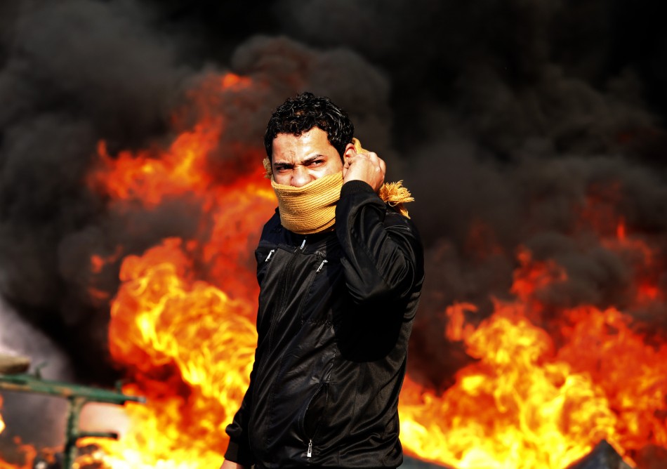 A protester stands in front of a burning barricade during the agitation in Cairo