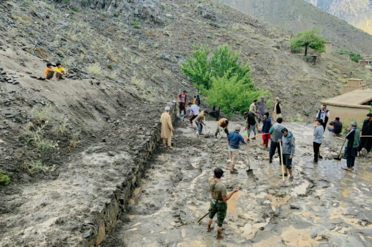 Afghan residents shovel mud following flash floods after heavy rainfall in Panjshir province in July 2024 -- scientists say climate change is spurring extreme weather events