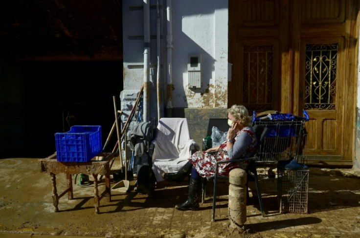 A woman rests in a street covered in mud in Paiporta, in the aftermath of deadly flooding in the region of Valencia