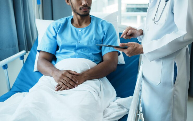 Male Doctor Talks to Male Patient Resting in Bed
